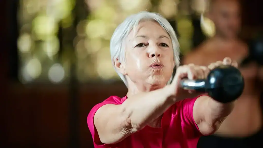 Older woman doing weight training Windlesham to help her strength and longevity 
