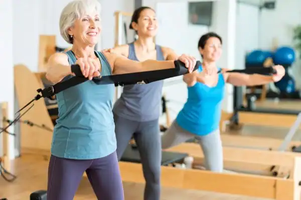 Toning Arms After 60: Empowering Womens Fitness Through Effective Weight Training 2 older woman doing weight training Windlesham and resistance in the gym to tone upper arms