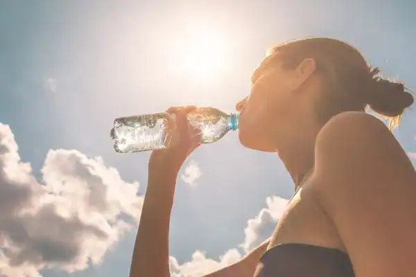Hydration: The Secret Ingredient for a Toned Stomach and Enhanced Fitness 3 Image of woman drinking water to hydrate Windlesham after run.