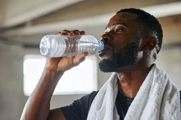 Hydration: The Secret Ingredient for a Toned Stomach and Enhanced Fitness 1 Image of man drinking water to improve hydration Windlesham after work out.